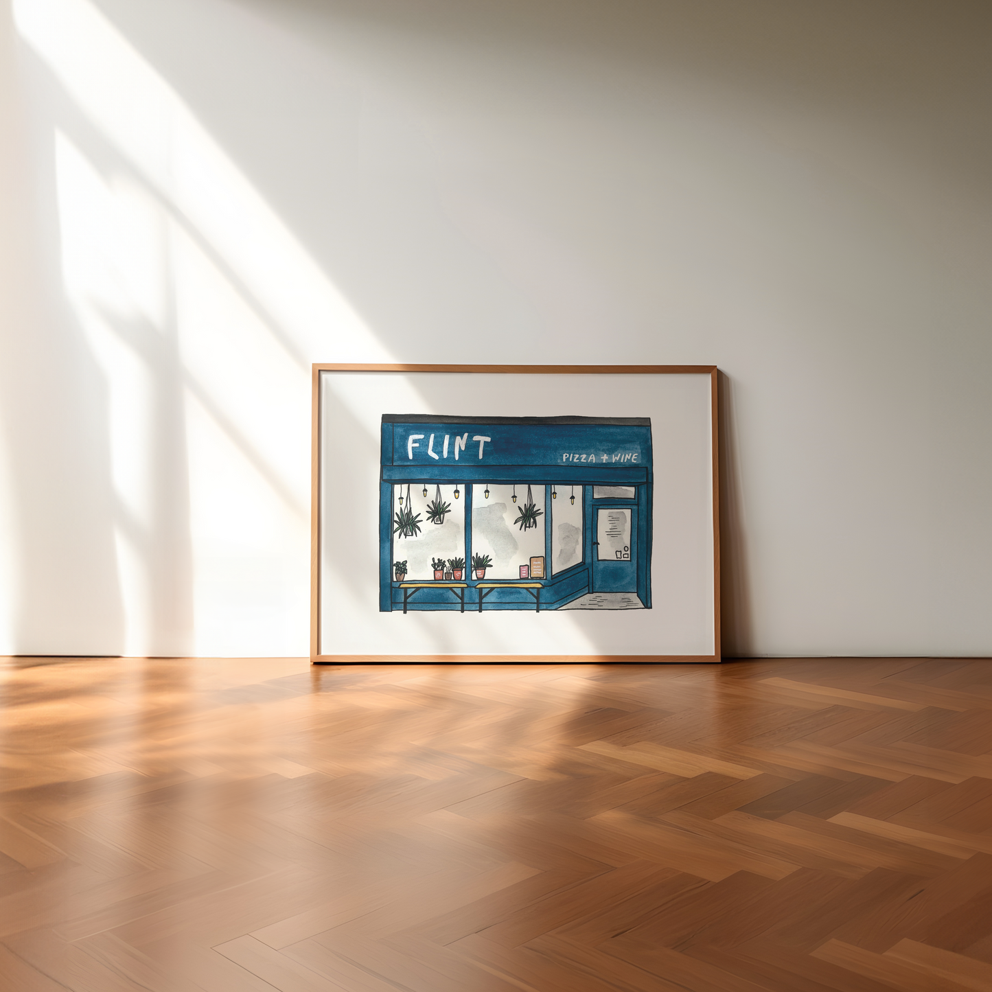 Framed artwork of a store front with 'FLINT' on the door, placed on a wooden floor.