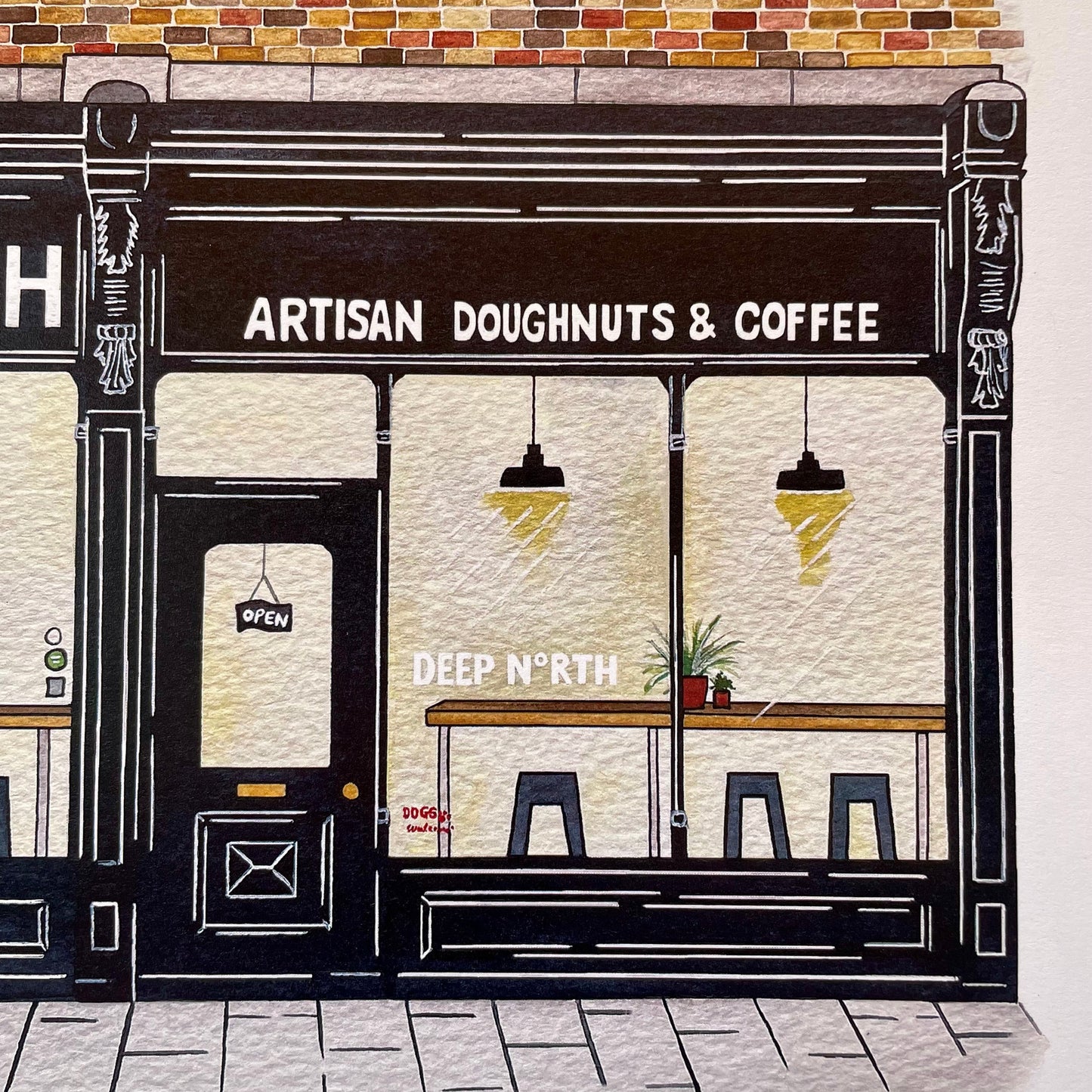 A hand-drawn illustration of a storefront with the text 'ARTISAN DOUGHNUTS & COFFEE' above a dark facade, cream windows, hanging lights, stools, and a brick roofline. The words 'DEEP N'RTH' appear in the window, and a small sign near the bottom reads 'tuesday only'.