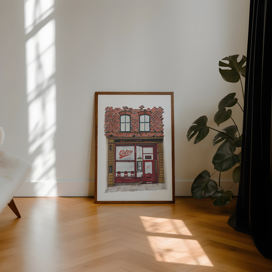 Framed artwork of Alvinos bar newcastle on a wall with a plant and sunlight casting shadows on a wooden floor.