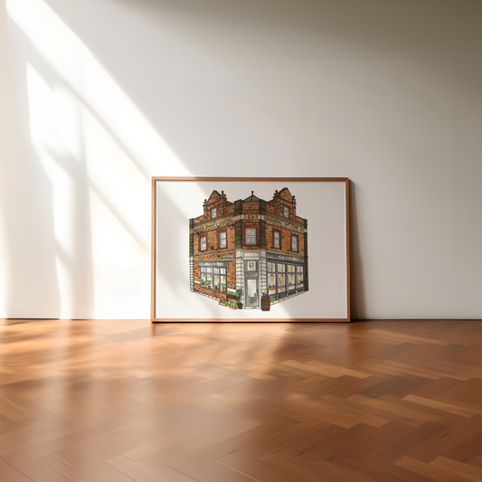 Framed artwork of a building on a white wall with wooden floor