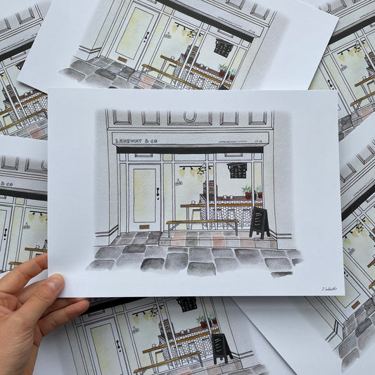 Hand holding a print of Laneway Coffee newcastle Upon Tyne with more illustrations in the background.