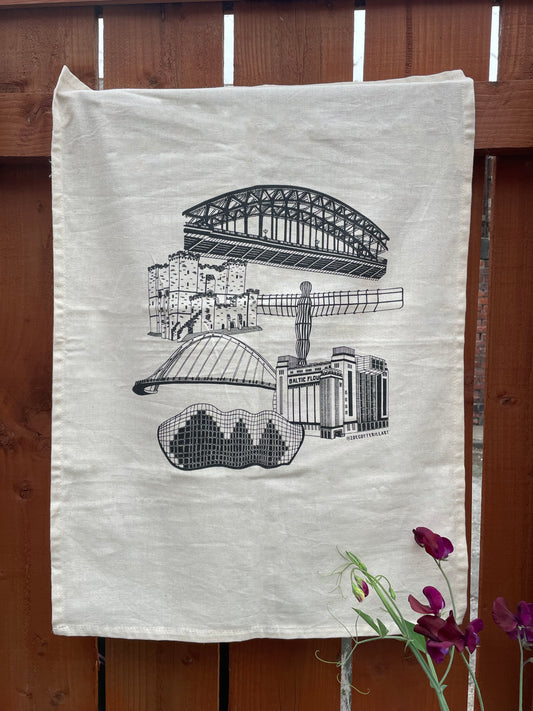 Teatowel with architectural landmarks of Newcastle Upon tyne, displayed hanging against a wooden background