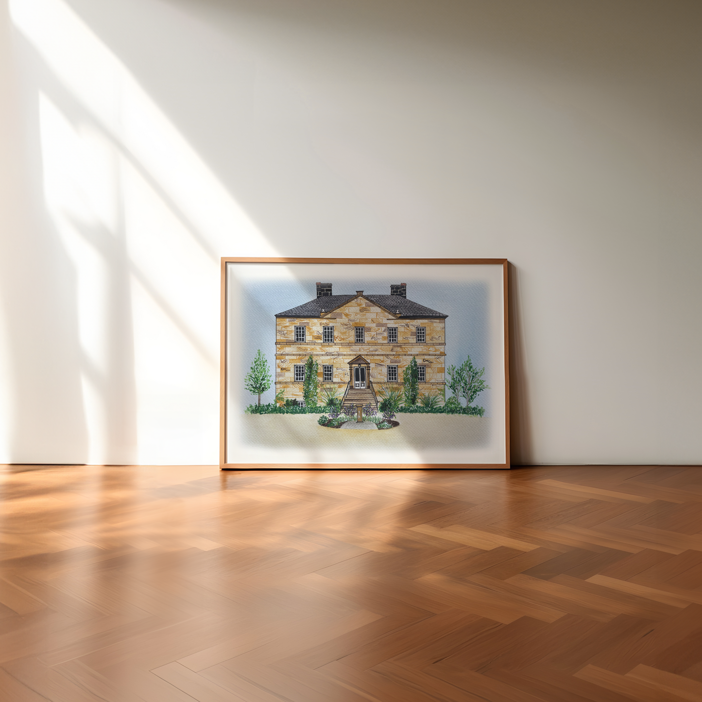 Framed artwork of a wedding venue on a white wall with wooden floor