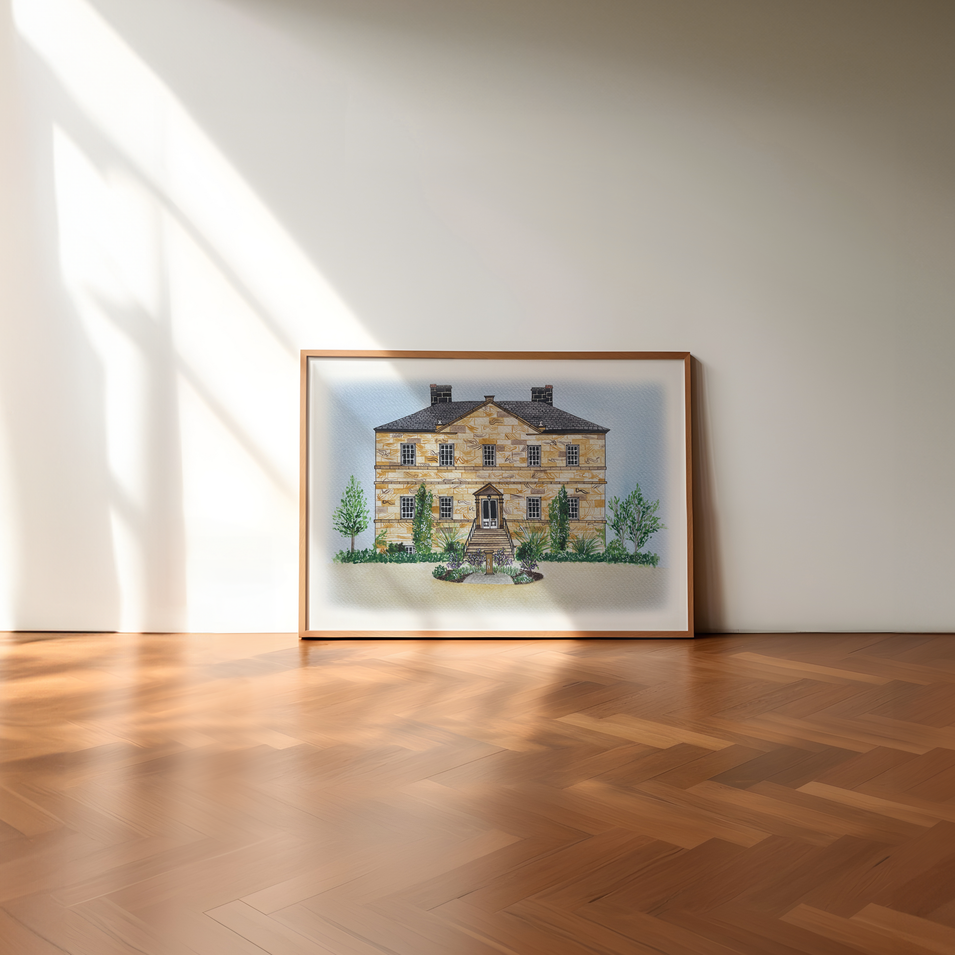 Framed artwork of a wedding venue on a white wall with wooden floor