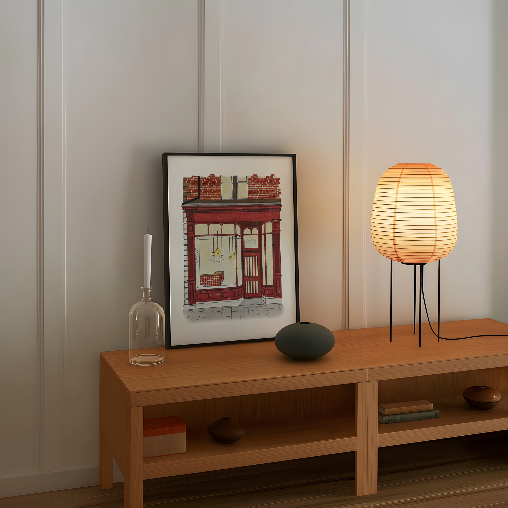 Wooden shelf with a framed picture of Roma coffee shop, candle, vase, and lamp against a white wall.