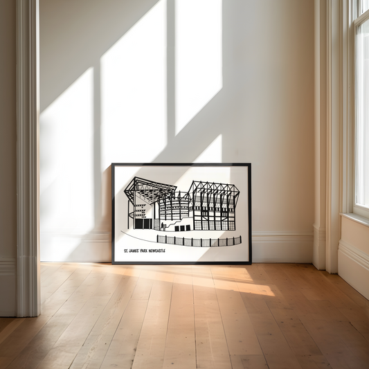 Framed architectural drawing of St James Park football stadium, Newcastle on a wall in a bright room with sunlight streaming through windows.