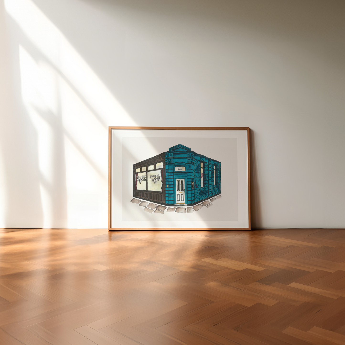 Framed artwork of a blue building on a white wall with wooden flooring