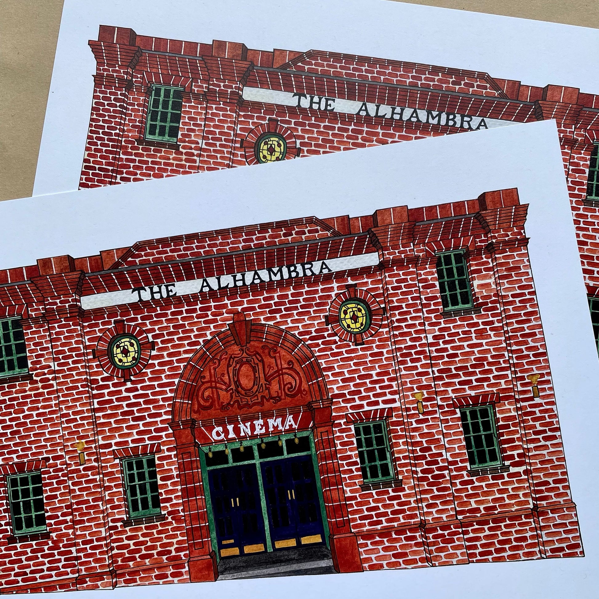 Red brick building with 'The Alhambra Cinema' sign on a white background