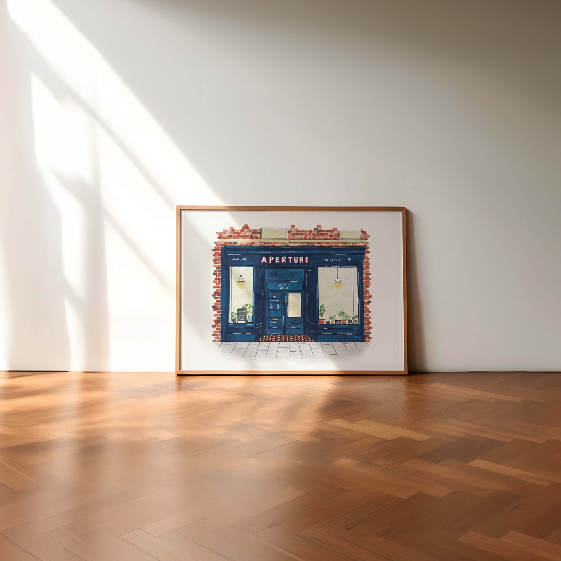 Framed artwork of a store front with 'Aperture' on a white wall.