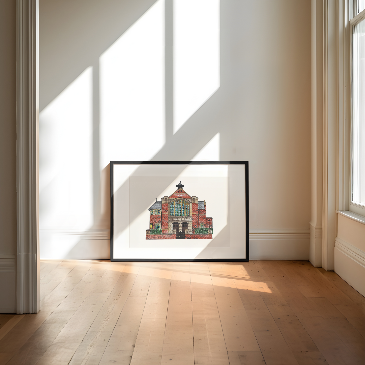 Framed artwork of a building on a wall in a bright room with sunlight streaming through windows.