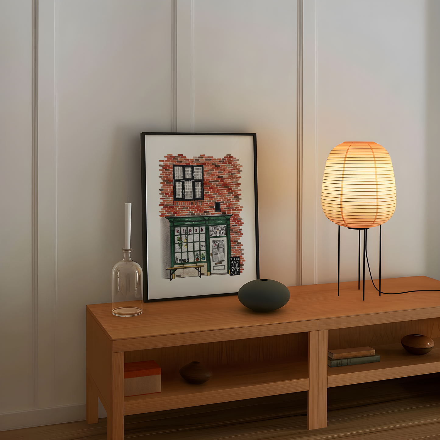 Wooden shelf with a framed picture, candle, vase, and lamp against a white wall.
