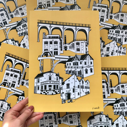 Hand holding a framed illustration of architectural designs on a yellow background with more illustrations in the background.