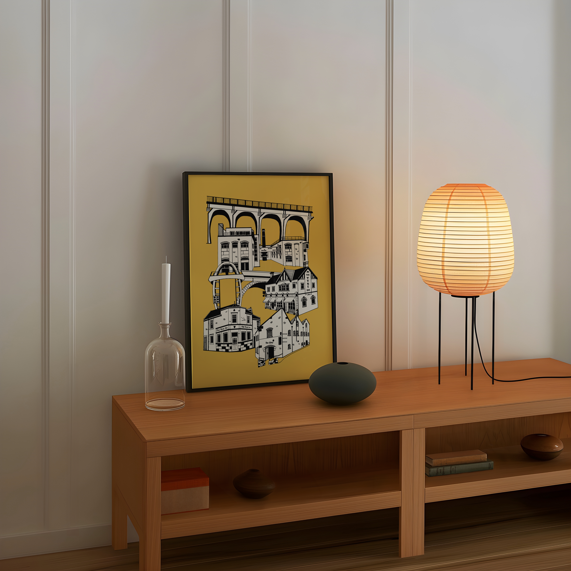 Wooden shelf with decorative items including a framed picture of ouseburn pubs, lamp, and vase against a white wall.