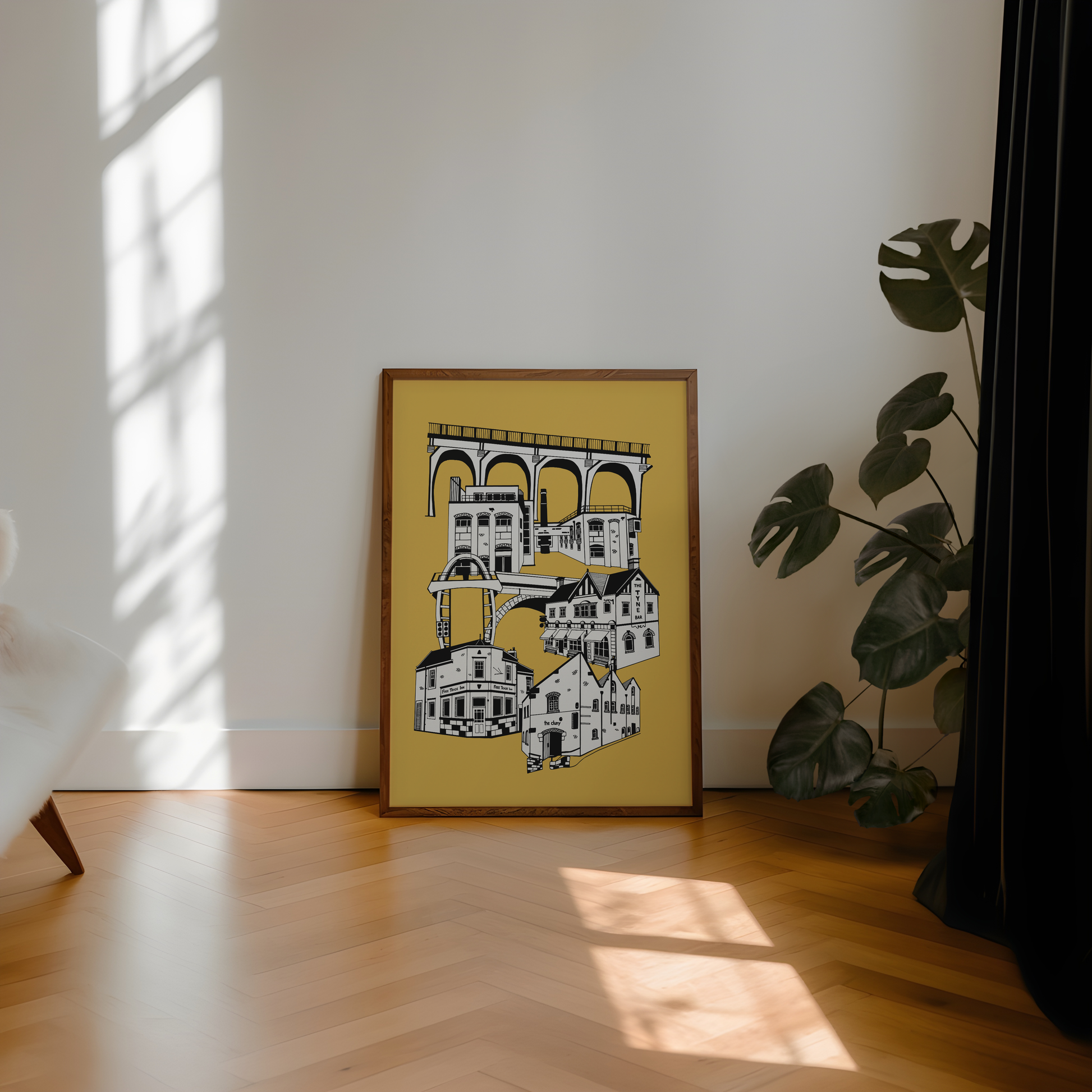 Framed artwork on a wall with a plant and sunlight casting shadows on the floor.